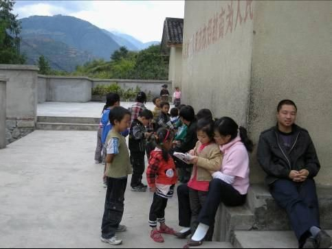 图说：老师们利用午休时间在屋檐下坐成一排，为孩子们辅导功课