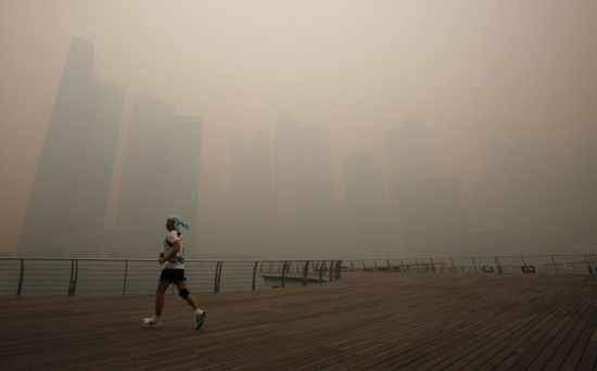 　　6月21日，新加坡海滨布道上的慢跑者，背景是新加坡的中心商业区笼罩在雾霾当中。新加坡空气质量达到危险地步，当地的正常商业和旅游活动陷入中断。