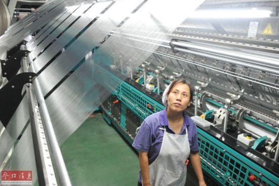 　　资料图片：6月26日，莆田华峰集团员工谭双利查看制造鞋服面料的高智能挡车机台。新华社记者林善传摄