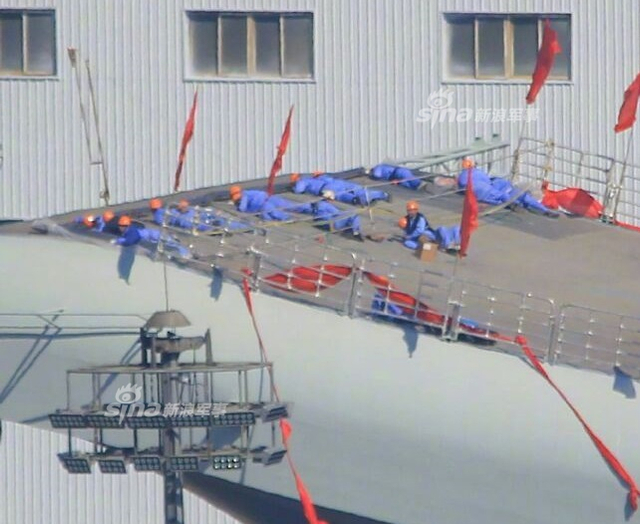 工人检查舰艏的情况:国产航母下水后继续施工