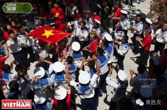 在敦谦沙洲上，越侨代表团与军民在越南国旗下唱歌。