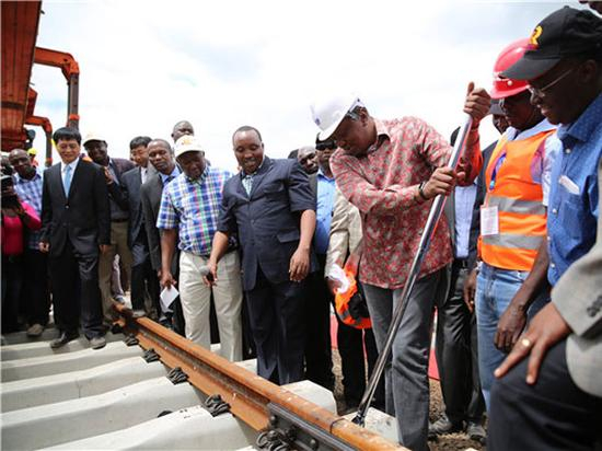 肯尼亚总统肯雅塔（著花衬衫）在中国驻肯大使刘显法陪同下视察铁路，并亲手铺轨