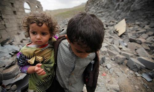 联军轰炸也门首都后，一个男孩儿带着妹妹在废墟之中寻找父母
