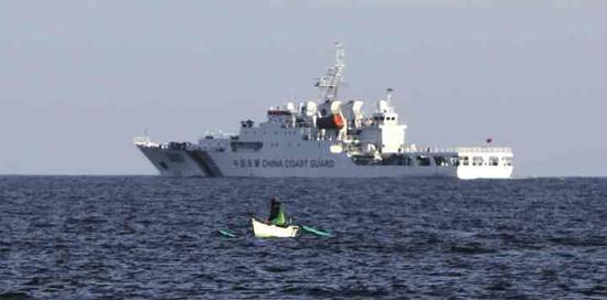 在该海域作业的菲律宾渔民，背景为中国海警船