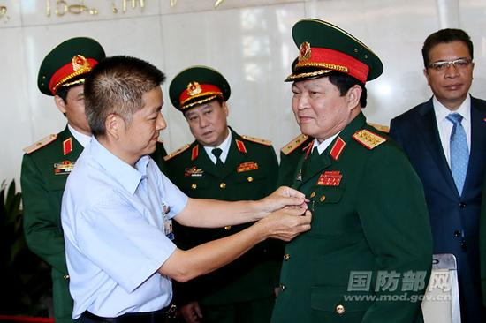 　　毛主席纪念堂管理局副局长邝宏志为越南中央政治局委员、中央军委副书记、国防部长吴春历大将佩带毛主席纪念章。李晓伟摄