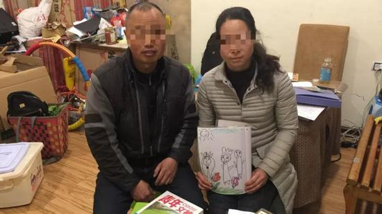 　　2019年3月17日，陈浩瀚父母准备了一箱书籍，计划第二天探视时送给陈浩瀚，陈妈妈手中捧着儿子幼儿园时画的“一家三口”。 新京报记者 韩茹雪 摄