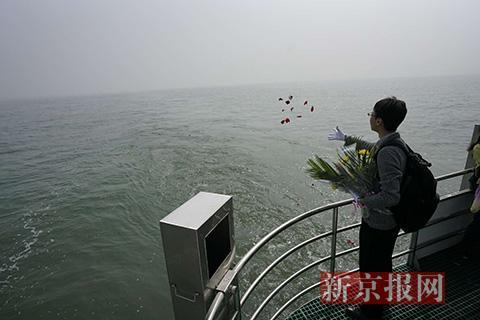 一位亲属在船尾抛洒花瓣。新京报记者 王飞 摄