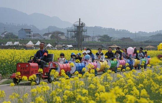  2023年4月1日，游客在杭州市临安区青山湖街道郎家村乘坐小火车在油菜花地里感受春日美景。（徐昱 摄）