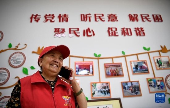 　　宁夏吴忠市利通区金花园社区党员王兰花在社区工作站与居民通电话（2021年6月16日摄）。新华社记者 王鹏 摄