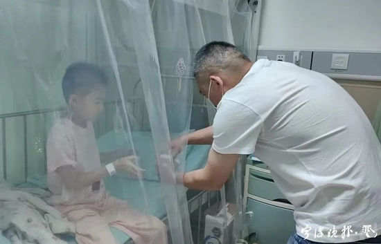  小凡住在单人无菌的层流床里，爸爸给她递药。记者 邱琼 摄