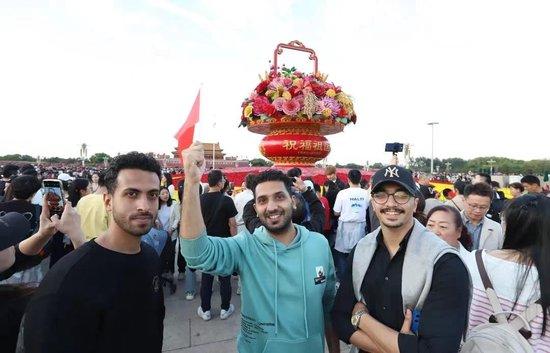 △2023年10月1日，三位来自阿尔及利亚的游客在北京天安门广场“祝福祖国”巨型花篮前留影。