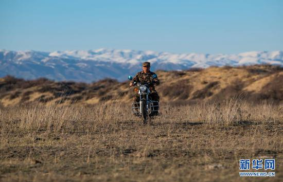 新疆生产建设兵团第10师185团职工马军武骑摩托行驶在管护辖区内（4月9日摄）。新华社记者 胡虎虎 摄