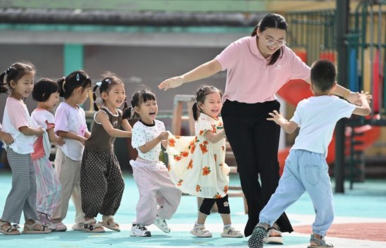 2025年9月10日，在山东省滕州市西岗镇中心幼儿园（柴里）分园，老师和小朋友一起玩“老鹰捉小鸡”趣味游戏。新华社发（李志军 摄）