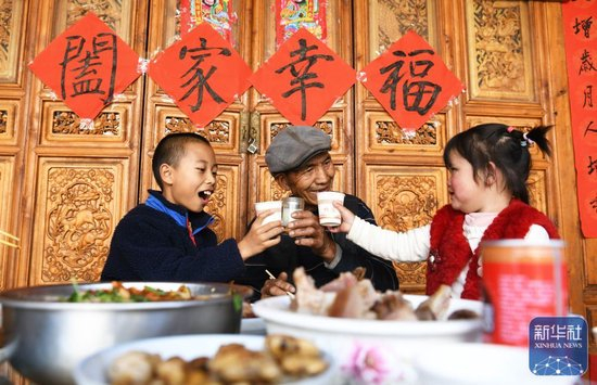  ↑ 2月16日，在云南省大理白族自治州剑川县马登镇文屏村，老人和孙辈吃年夜饭。新华社发（赵庆祖 摄）