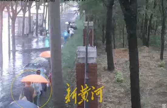 手持橙色雨伞的苗大广在台阶上前行，其左侧的人行道已被积水淹没。受访者供图&nbsp;