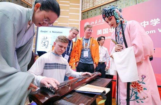  3月20日，在北京大学，中国学生在指导美国华盛顿州中学生代表团的成员弹奏古琴。