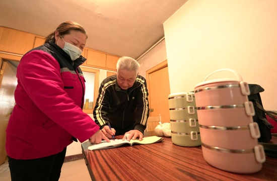  河北省邢台市康宁智慧社区养老服务中心工作人员（左）把午餐送到檀成海老人家中（2022年1月6日）。新华社发 （陈雷 摄）