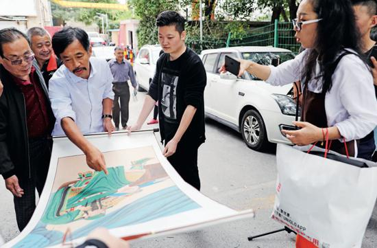 沈巍观看粉丝送他的画。摄影/本刊记者&nbsp;董洁旭