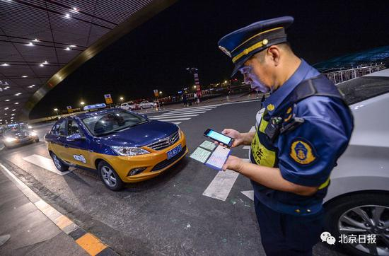 执法人员通过手持终端对出租车驾驶员信息进行核查。