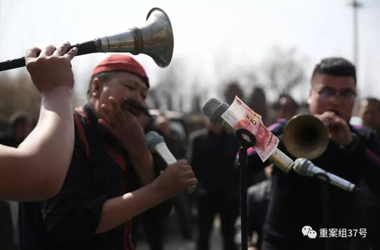 　　▲三平（红帽子）正在表演口技，麦克风上夹着主家给的赏钱。&nbsp; &nbsp; &nbsp;新京报记者&nbsp;尹亚飞&nbsp;摄