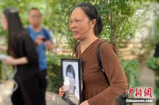 谢雕母亲带着谢雕的遗照走出法院 中新网 杨雨奇 摄