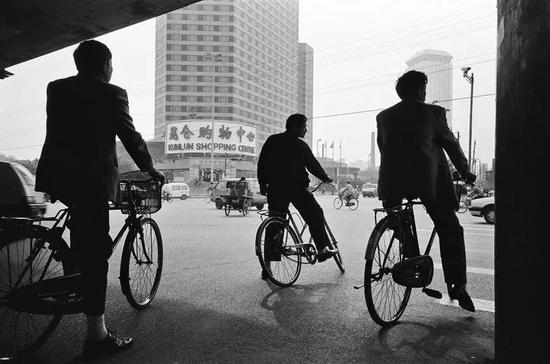△&nbsp;1996年，北京，三元东桥附近，三个上班族骑着脚踏车正准备穿过路口。