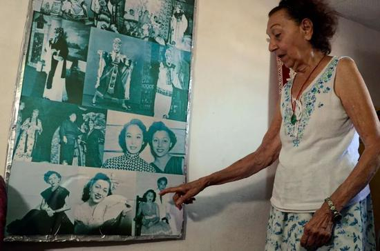 何秋兰在家中展示自己年轻时表演粤剧的照片。新华社发（华金·埃尔南德斯摄）