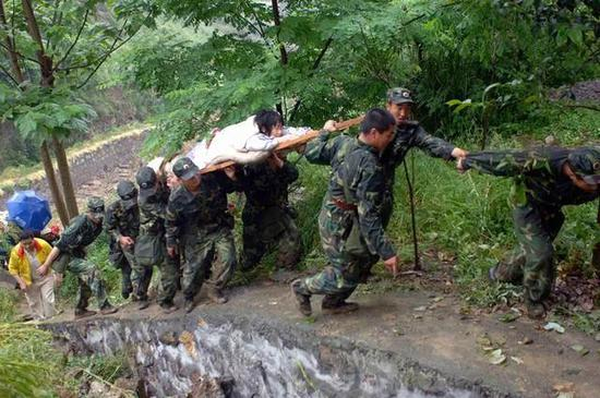 2008年5月13日，救援官兵抬着一位幸存的小姑娘爬上斜坡。图源：江毅|新华社