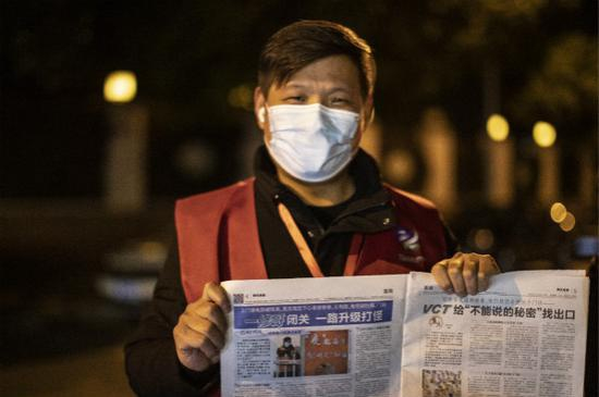 图说：“一修哥”葛庆海拿着写有他故事的那期新民晚报。