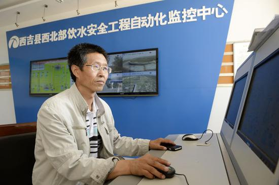 在宁夏西吉县一处农村饮水安全工程供水点，工作人员在操作自动化设备调配水源（2014年7月17日摄）。新华社记者 王鹏 摄