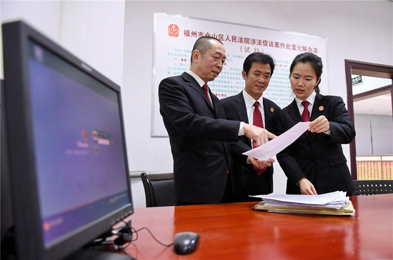 福建省福州市仓山区人民法院工作人员李扬（右）和同事在研究处理12368诉讼服务热线的群众意见（2019年1月17日摄）。服务热线主要负责法律咨询、案件查询、联系法官、收集意见建议等，为人民群众提供精准、便捷的服务。新华社记者 林善传 摄