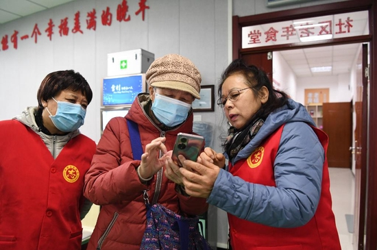  河北省承德市滨河社区志愿者帮助老人通过智慧点餐系统订餐（2021年12月16日）。新华社记者 朱旭东摄