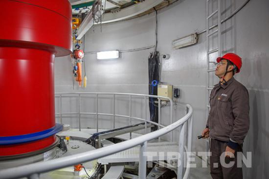 图为刘伟在检查水轮发电机组。