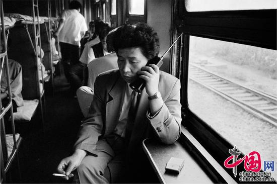  1994年，沈阳——大连。改革开放后做生意的乘客在卧铺车厢拿着当时最时髦的大哥大联系生意。王福春摄影