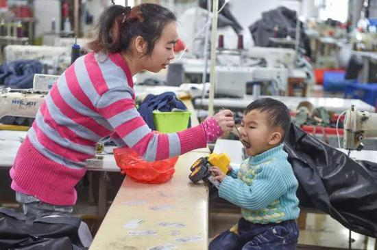 黄爱华在工厂给聪聪喂午饭。