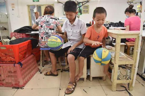 欧秋鸿（左二）、欧春鸿两兄弟在父母的工位旁比赛拍球。