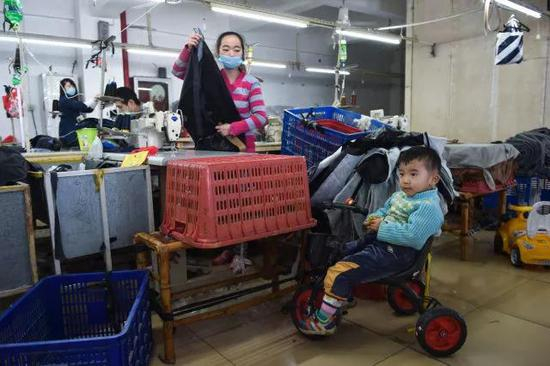 黄爱华在工作之余照看在旁边骑玩具车的聪聪。