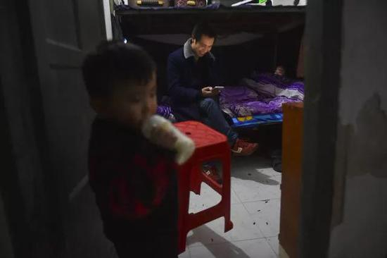 聪聪在宿舍门口喝奶，累了一天的父母在床上看手机。