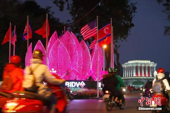  当地时间2月25日，胡志明主席纪念堂附近形似越南“国花”金莲花的花灯亮起灯光，美、朝、越三国国旗围绕花灯形成圆形。中新社记者富田 摄