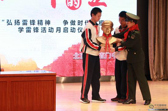 雷锋班班长走进东直门中学讲述雷锋故事。第26届雷锋班班长张阳把雷锋塑像赠送给三校的同学们。徐鹏 摄。