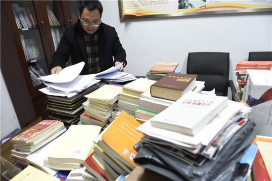 四川乐山市公路管理局工作人员在公路管理局原党委书记、局长王川的办公室整理书籍和文件（2017年2月13日摄）。王川在实地勘察小凉山精准扶贫交通项目时，突遇山岩崩塌，与其他6位同事殉职，年仅53岁。新华社记者 刘坤 摄
