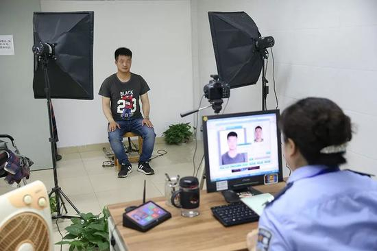 　　2019年5月14日，崇州市行政审批局。民警正在给王永福拍证件照，用来办理身份证。 新京报记者 尹亚飞 摄