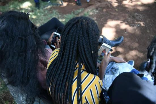 克莱尔·芬蒂（中）与好友浏览Vskit上的短视频。新华社记者李琰摄