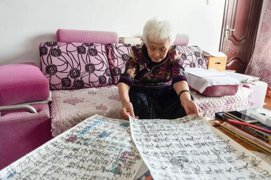 在黑龙江省绥化市北林区的家中，姜淑梅老人在家中翻看自己练过的字（9月12日摄）。新华社发 （谢剑飞 摄）