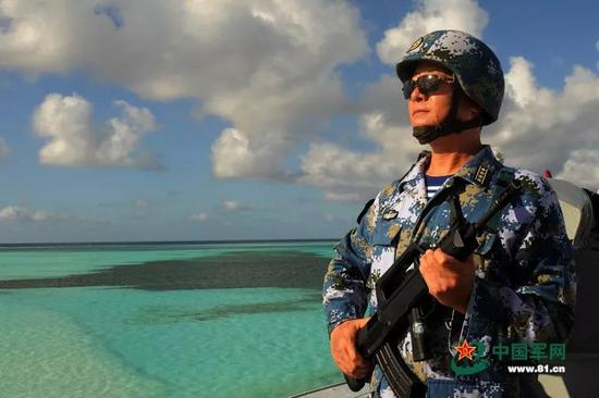 2016年慰问守礁部队期间，杨志亮挎上冲锋枪替战士站岗。 来源：中国军网