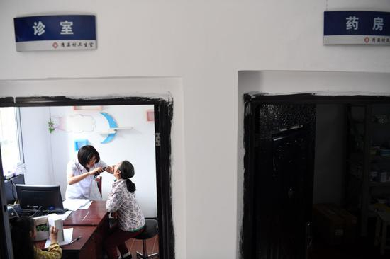  张清语的妈妈徐晓婵在清溪村卫生室内为村民看病。