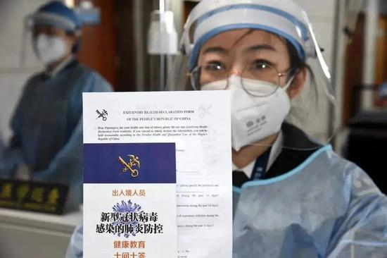  工作人员手持《中华人民共和国出/入境人员健康申明卡》