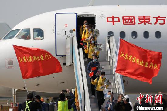  江苏医疗队员们手捧鲜花走出机舱。　泱波 摄