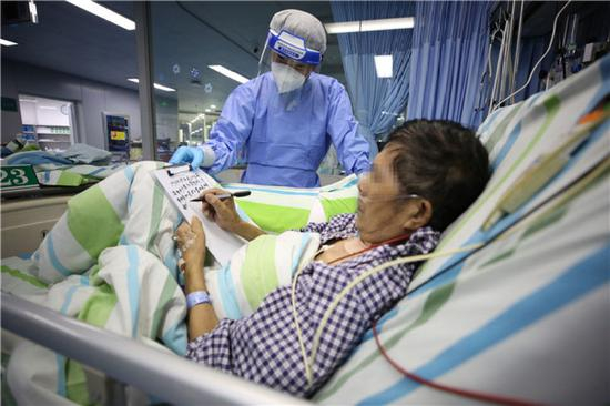 4月20日，在武汉大学中南医院ICU，患者刘先生在病床上写感谢信。新华社发（李晗 摄）