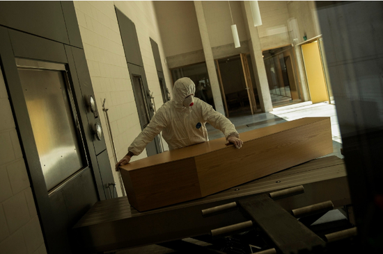  比利时一名工人在搬运疑似感染者的遗体，图源：美联社